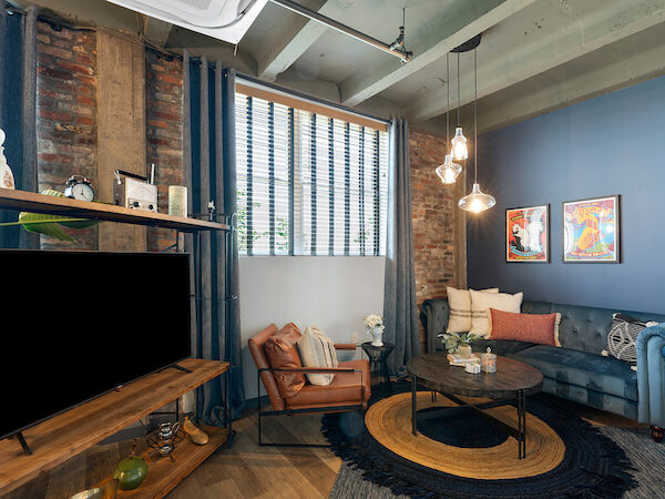 This image shows a cozy living room with a blue and white color scheme, featuring a sofa, armchair, coffee table, TV, and decorative items.