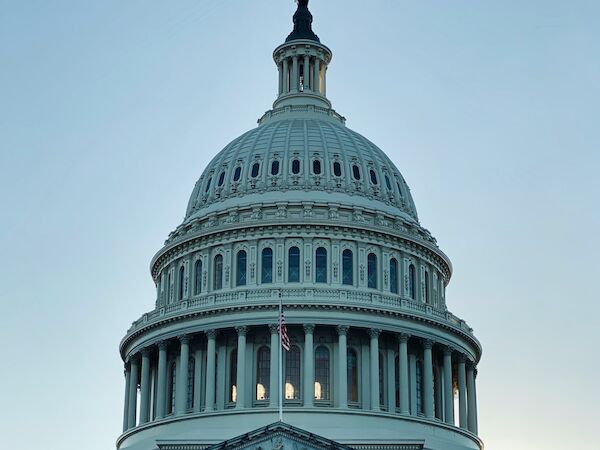 The image shows the United States Capitol building with its iconic dome at dusk.