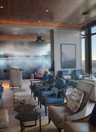 A modern lounge featuring comfortable seating, large windows with scenic views of the waterfront, and contemporary decor with a city mural.